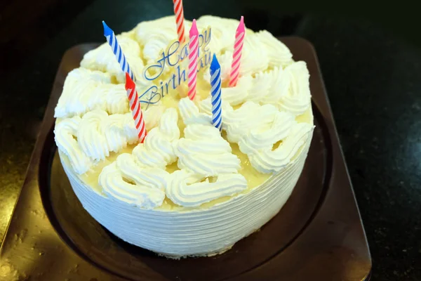Torta di compleanno con candele di colore su sfondo nero — Foto Stock