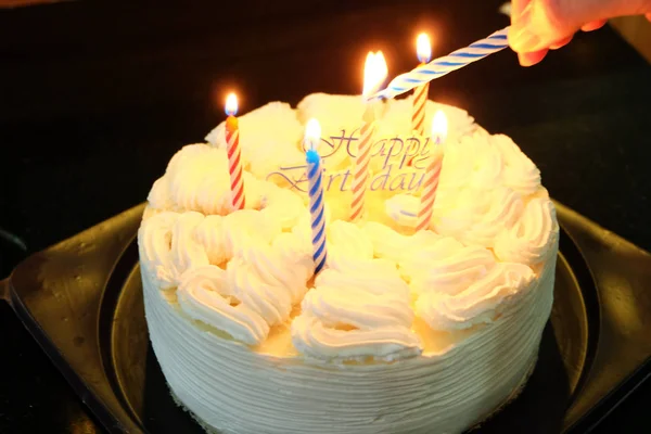Bolo de aniversário feliz com cores de velas e fundo de luzes brilhantes — Fotografia de Stock