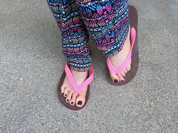 Szandál, Close Up lány lila köröm és a lábak rózsaszín szandált viselt, az utcai háttér — Stock Fotó