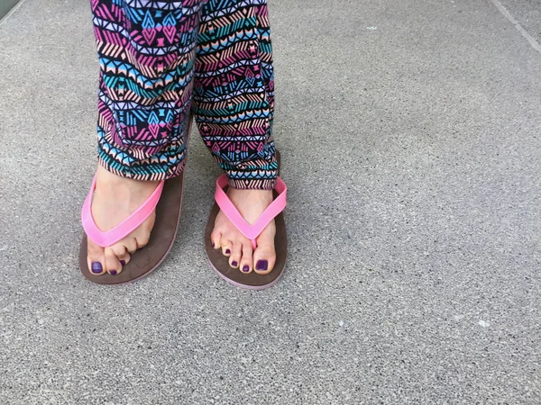 Sandalia, de cerca en las uñas y pies violetas de la muchacha con sandalias rosadas en el fondo de la calle — Foto de Stock