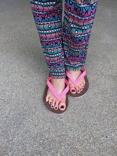 Sandál, Detailní záběr na dívčí fialové nehtů a nohou na sobě růžové sandály na ulici pozadí — Stock fotografie