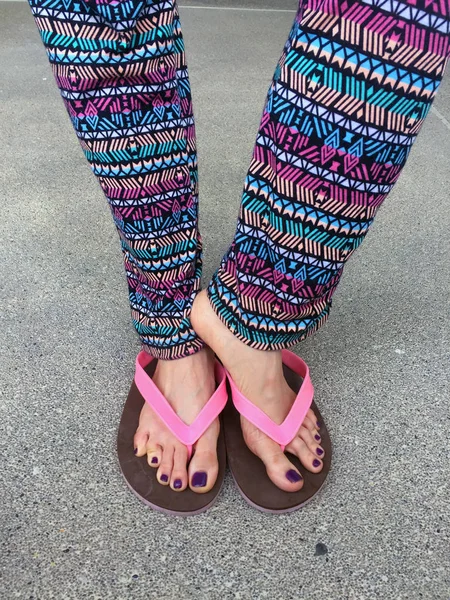 Szandál, Close Up lány lila köröm és a lábak rózsaszín szandált viselt, az utcai háttér — Stock Fotó