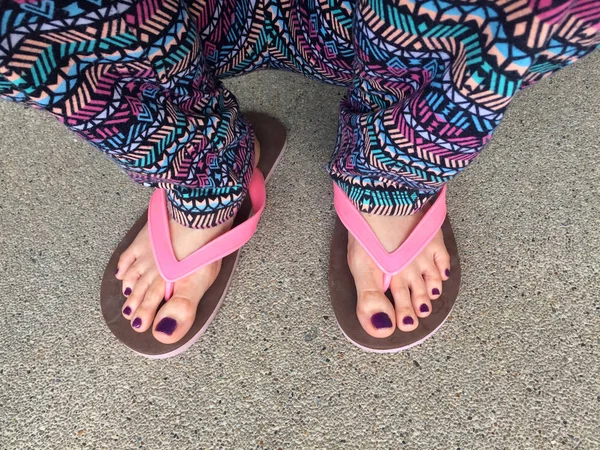 Sandalia, de cerca en las uñas y pies violetas de la muchacha con sandalias rosadas en el fondo de la calle — Foto de Stock