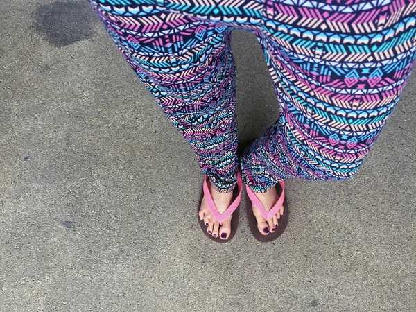 Sandal, kapatmak kız mor çivi ve sokak arka plan üzerinde pembe sandalet giyen ayakları üzerine