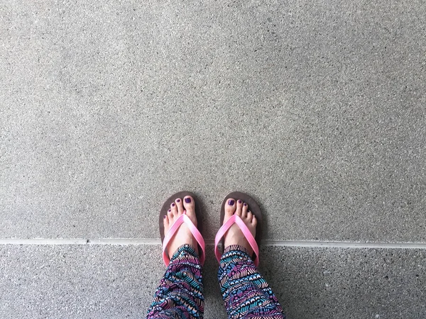 Sandal, kapatmak kız mor çivi ve sokak arka plan üzerinde pembe sandalet giyen ayakları üzerine