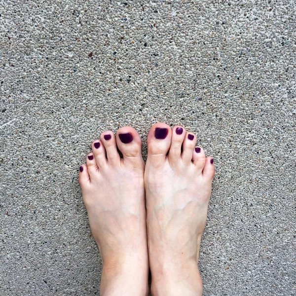 Krásné nehty, zblízka bosýma nohama a Červený lak na nehty na Cement podlahu pozadí ženy — Stock fotografie