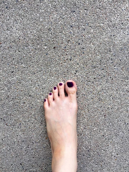 Красивый ногтей, крупным планом женские голые ноги и красный лак ногтей на цементном этаже — стоковое фото