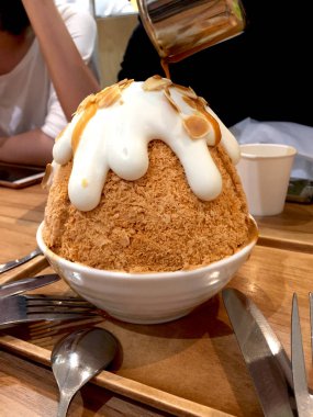 Koreli tatlı-Bingsu süt çayı buz tıraş ve ahşap masa arka planda çay dökme