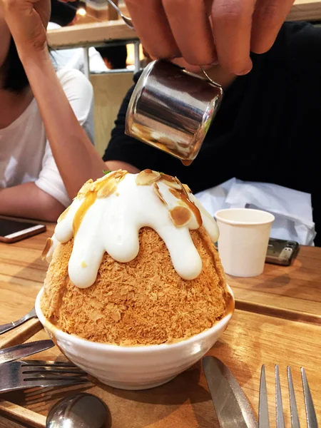 Sobremesa coreana - Barbear de gelo de chá de leite de Bingsu e chá de derramamento em fundo de mesa de madeira — Fotografia de Stock