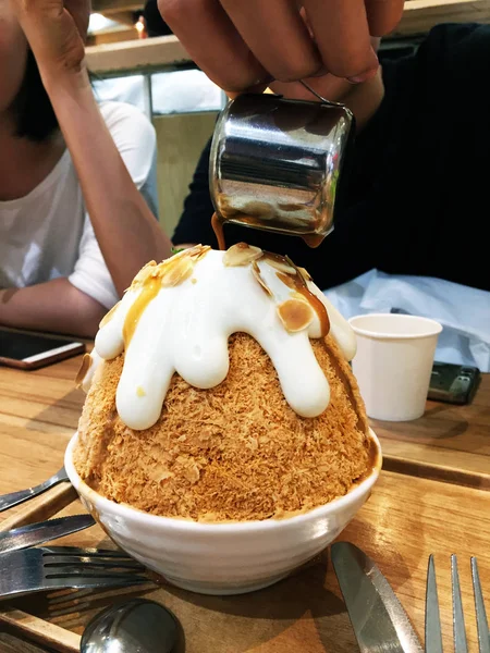 Sobremesa coreana - Barbear de gelo de chá de leite de Bingsu e chá de derramamento em fundo de mesa de madeira — Fotografia de Stock