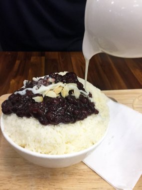 Koreli tatlı-Bingsu kırmızı fasulye buz fıstık ve ahşap masa arka planda süt dökme ile tıraş