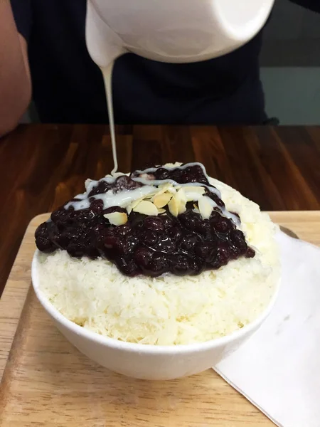 Postre coreano - Bingsu Afeitado de hielo de frijol rojo con cacahuete y leche de verter sobre fondo de mesa de madera —  Fotos de Stock