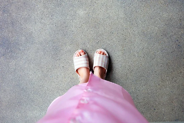 Розовый спальный костюм и тапочки, крупным планом женщин Розовые клетчатые тапочки, стоящие на полу — стоковое фото