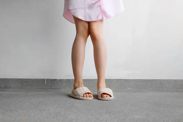 Traje de dormir rosa y zapatillas, primer plano de las mujeres Rosa zapatillas a cuadros de pie en el piso —  Fotos de Stock