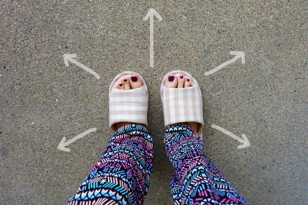 Womans desgaste casa chinelos pés com setas desenhado escolhas direção no fundo de concreto — Fotografia de Stock