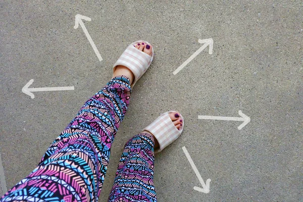 女人穿家庭拖鞋脚与箭头绘制选择方向的具体背景 — 图库照片