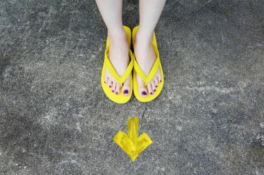 Sarı ok yönünde. Kadının sandalet ayak Violet ile çimento zemin üzerine pedikür tırnak