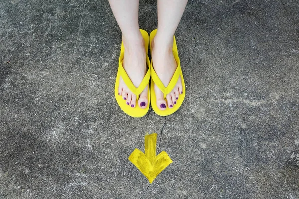 Sarı ok yönünde. Kadının sandalet ayak Violet ile çimento zemin üzerine pedikür tırnak