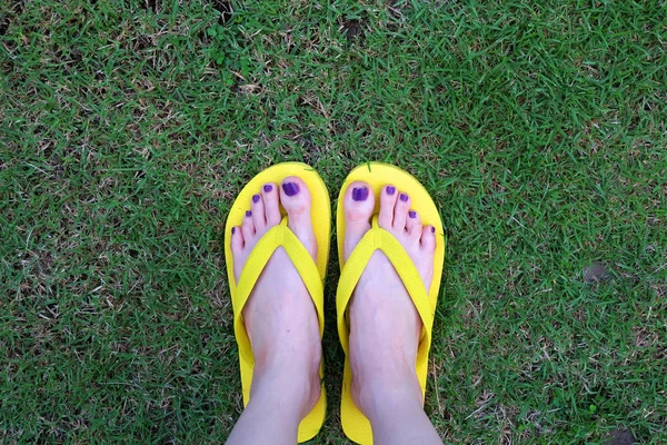 Sarı sandal. Selfie Womans sandalet ayak Violet ile çim yeşil arka plan üzerinde boya pedikür tırnak