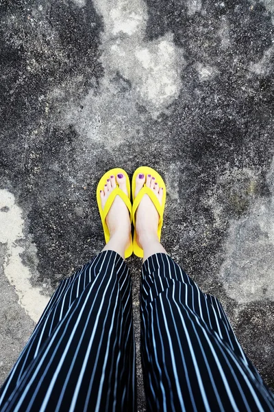 Yellow Sandals. Selfie Womans Sandals Feet with Violet Nail Pedicure of Paint on Cement Background