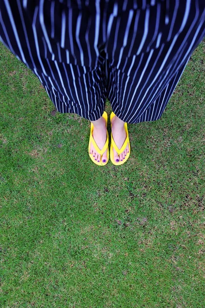 Sarı sandal. Selfie Womans sandalet ayak Violet ile çim yeşil arka plan üzerinde boya pedikür tırnak