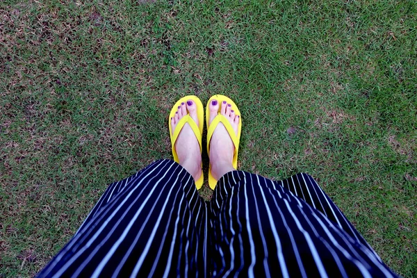 Sarı sandal. Selfie Womans sandalet ayak Violet ile çim yeşil arka plan üzerinde boya pedikür tırnak
