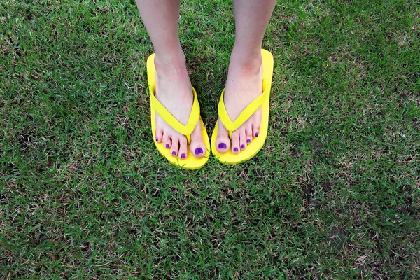 Sarı sandal. Selfie Womans sandalet ayak Violet ile çim yeşil arka plan üzerinde boya pedikür tırnak