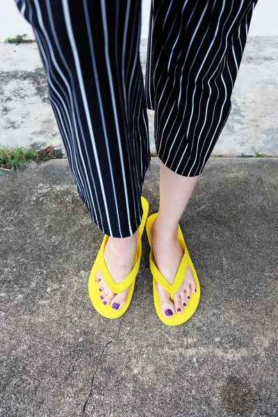 Yellow Sandals. Selfie Womans Sandals Feet with Violet Nail Pedicure of Paint on Cement Background