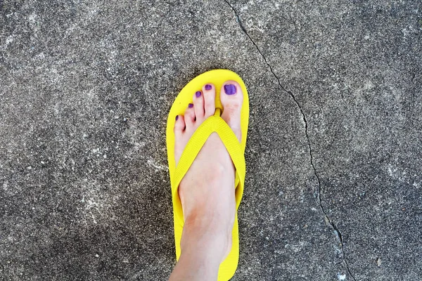 Sárga szandál. Selfie Womans szandál láb-lila festék Cement háttér pedikűr köröm — Stock Fotó
