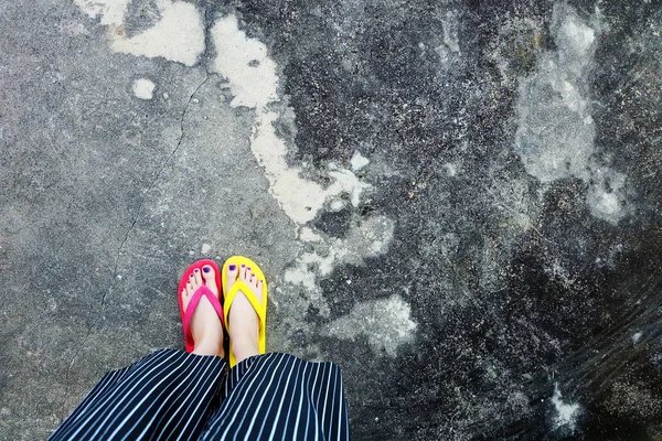 Czerwone i żółte klapki. Selfie kobieta ubrana Flip Flop, stojąc na Cement — Zdjęcie stockowe