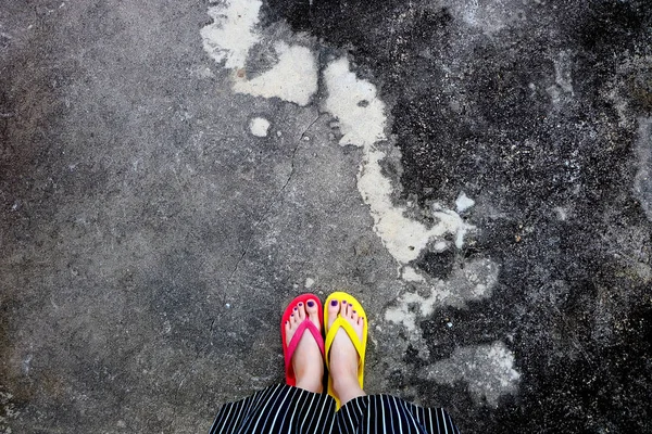 Rote und gelbe Flip-Flops. Selfie-Frau mit Flip-Flop steht auf Zement — Stockfoto