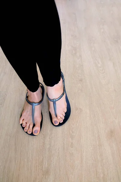 Kız bacaklar ve ayaklar ahşap arka plan üzerinde siyah sandalet giymek — Stok fotoğraf