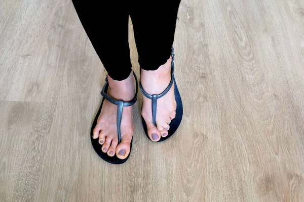 여자 다리와 발 나무 배경에 검은색 샌들을 착용 — 스톡 사진