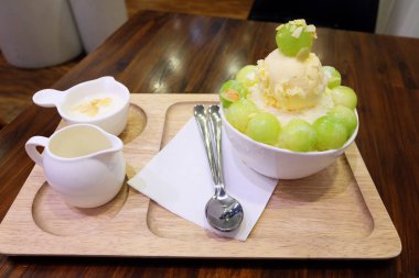 Buz tatlı tepsi ile Tepesi üzerinde ve ahşap masa arka plan üzerinde süt kavun Bingsu Korece traş