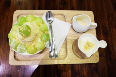 Buz tatlı tepsi ile Tepesi üzerinde ve ahşap masa arka plan üzerinde süt kavun Bingsu Korece traş