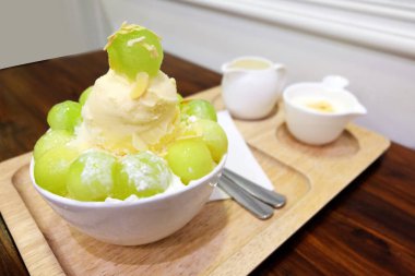 Buz tatlı tepsi ile Tepesi üzerinde ve ahşap masa arka plan üzerinde süt kavun Bingsu Korece traş