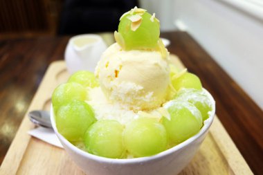 Buz tatlı tepsi ile Tepesi üzerinde ve ahşap masa arka plan üzerinde süt kavun Bingsu Korece traş