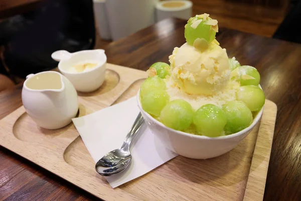 メロン Bingsu 韓国トッピング付きのトレイのアイス デザートと木製のテーブル背景にミルクを剃毛 — ストック写真