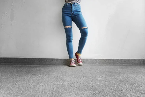 Röda Sneakers. Kvinnans ben i röda Sneakers och blå Jeans på golvet bakgrund — Stockfoto