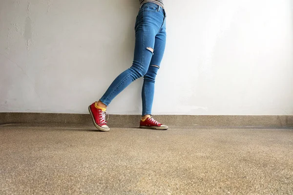 红色运动鞋女人腿在红色运动鞋和蓝色牛仔裤在地板背景 — 图库照片
