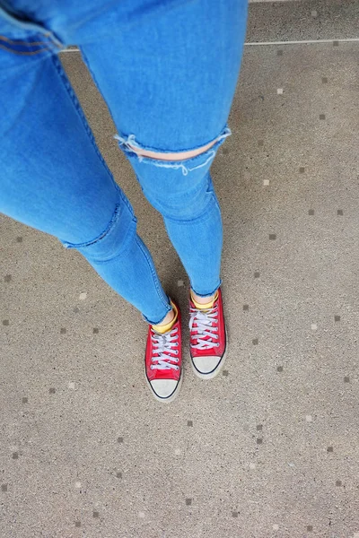 Närbild av röda Sneakers. Selfie kvinnans ben i röda Sneakers och blå Jeans på golvet bakgrund — Stockfoto