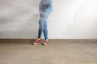 Kırmızı spor ayakkabılar. Kadının bacakları kırmızı spor ayakkabılar ve Mavi Jeans ile kat arka plan üzerinde beyaz duman
