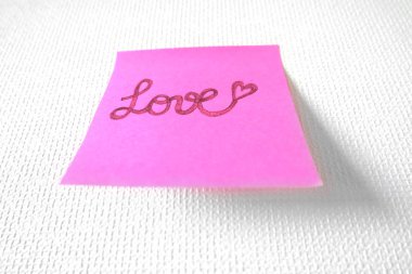 Pembe kağıt sopa not büyük bir beyaz arka plan üzerinde herhangi bir kullanım için yazılmış aşk metni ile.