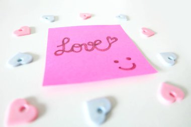 Pembe etiket kağıt kayda göre herhangi bir kullanım için büyük bir beyaz arka plan üzerinde aşk sözle çizilmiş gülümsemek yüz.