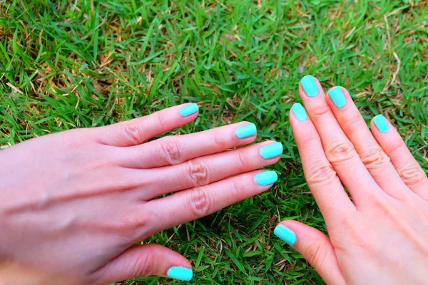 Close Up Green Manicure Nail. Beautiful Females Hand Nails Polish on the Wood Floor Background