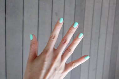 Yeşil manikür tırnak kapatın. Güzel kadın el ahşap zemin zemin üzerine Lehçe çivi