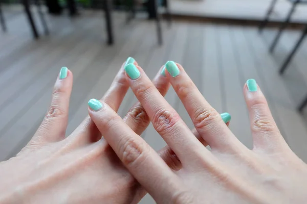 关闭绿色指甲指甲 美丽的女性手指甲抛光木地板背景 — 图库照片