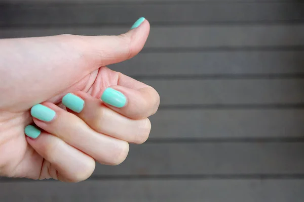 关闭绿色指甲指甲 美丽的女性手指甲抛光木地板背景 — 图库照片
