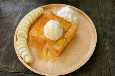 Muz ve ahşap his üzerinde vanilyalı dondurma ile bal tost. Ekmek kadar yakın tereyağlı ekmek ile çırpılmış kremalı tatlı ahşap tabak üzerinde arka plan büyük herhangi bir kullanım için.