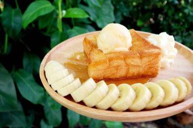 Muz ve ahşap his üzerinde vanilyalı dondurma ile bal tost. Ekmek kadar yakın tereyağlı ekmek ile çırpılmış kremalı tatlı ahşap tabak üzerinde arka plan büyük herhangi bir kullanım için.